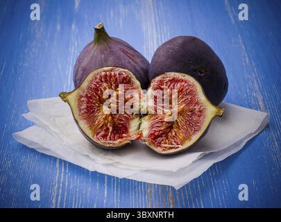 Three ripe figs on blue background, close up Stock Photo