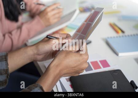 A vibrant design team collaborates on graphics in a modern office fostering creativity and innovation in their projects Stock Photo