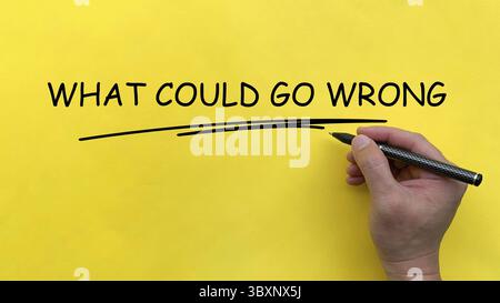 Hand writing What Could Go Wrong text on yellow cover board Stock Photo
