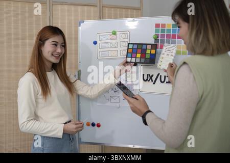 Ux developer and ui designer presenting mobile app interface design on whiteboard in meeting at office. Creative digital development mobile app agency Stock Photo