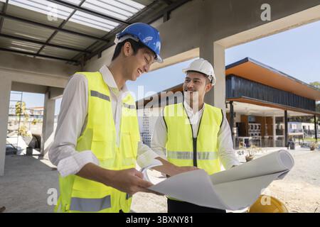 Two construction workers reviewing plans on site, emphasizing communication and strategic planning Stock Photo
