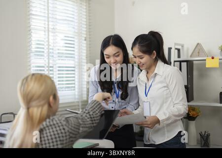 A diverse business team of three women collaborating and enthusiastically reviewing documents in a bright office environment, showcasing teamwork and Stock Photo