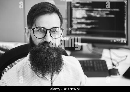 Closeup portrait of a serious computer programmer developer working in IT office, sitting at desk and coding a project in software development company Stock Photo
