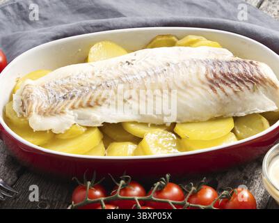 Fish cod baked in the oven with potatoes and spice - healthy diet healthy food. Dark old wooden rustic gray background, side view Stock Photo