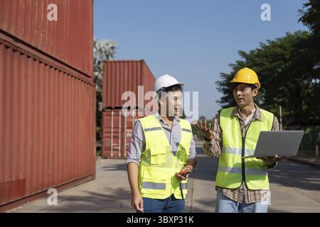 Two engineers engage in a strategic discussion about logistics while using a laptop, emphasizing modern planning techniques Stock Photo