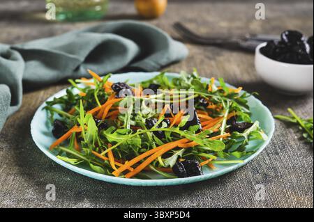 Food, Delicious salad of carrots, arugula and prunes on a plate on the table Stock Photo