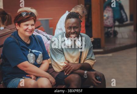 black man and woman sitting on a bench in a park Stock Photo