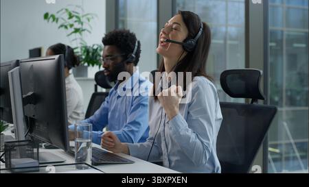 Callcenter success multiethnic operators work computer helpline service agency Caucasian business woman clenching fist successful online trading Stock Photo