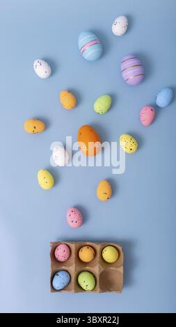 Beautiful decorative multicolored eggs are scattered on a light blue background, top view Stock Photo