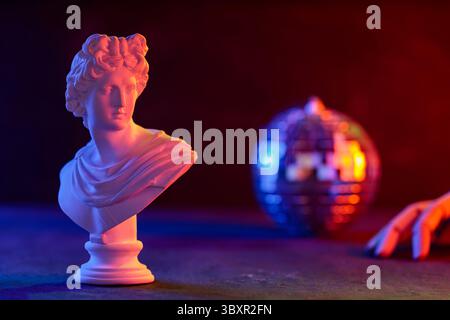 Classical Sculpture Bust Cradled in Mannequin Hand Neon Disco Ball Stock Photo