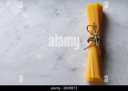 Raw Spaghetti Bundle Tied with Jute Twine on Concrete Surface Copy Space Stock Photo