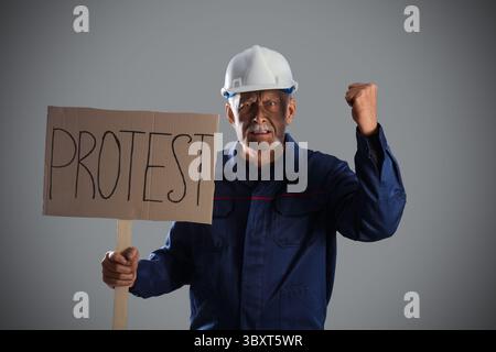 Protesting miner man with placard on grey background Stock Photo