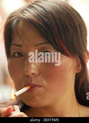 A Chinese woman lights up a cigarette at a cafe in downtown Beijing, July  14, 2006. The Chinese government has called for stronger measures to curb  smoking in the world's biggest cigarette