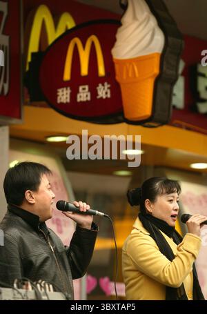 March 1, 2007, BEIJING, CHINA: Two singers perform outside a McDonalds hoping to attract more business in downtown Beijing, China, on March 01, 2007.  For decades, American icons such as McDonalds, Pizza Hut and Kentucky Fried Chicken have spread around the globe. Their success has transformed diets and dining habits, sparking an occasional backlash in some countries over the loss of home-grown tastes and eateries. (Credit Image: © Stephen Shaver/ZUMA Press Wire) Stock Photo