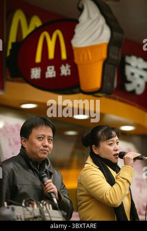 March 1, 2007, BEIJING, CHINA: Two singers perform outside a McDonalds hoping to attract more business in downtown Beijing, China, on March 01, 2007.  For decades, American icons such as McDonalds, Pizza Hut and Kentucky Fried Chicken have spread around the globe. Their success has transformed diets and dining habits, sparking an occasional backlash in some countries over the loss of home-grown tastes and eateries. (Credit Image: © Stephen Shaver/ZUMA Press Wire) Stock Photo