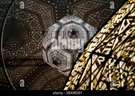 In D.C., a hanging light fixture casts a geometric shadow on the ceiling, mirroring a nearby structure's design, creating a captivating effect. Stock Photo
