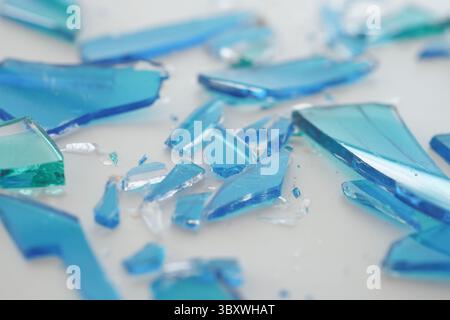 Blue glass shards scattered on a white surface Stock Photo