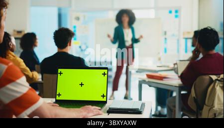 Green screen, laptop and lecture with students in classroom for college portal, learning and lesson notes. University, education and teaching with Stock Photo