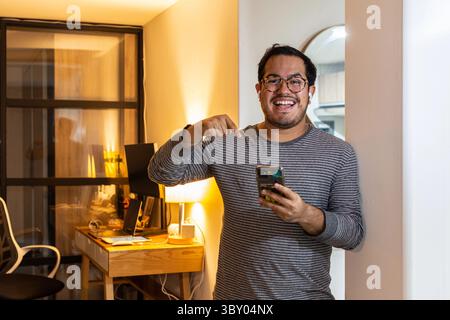 Surprised Man Reading Unexpected News on Smartphone at Home Stock Photo