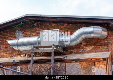 Large metallic duct system attached to a brick wall, showcasing industrial design elements and ventilation infrastructure. Stock Photo
