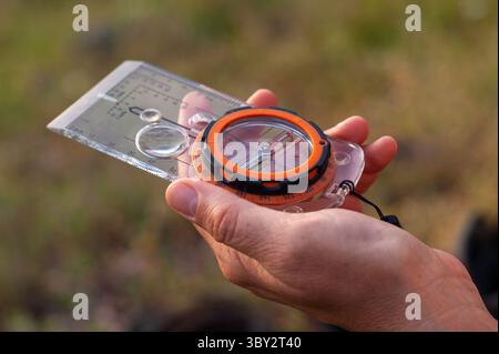 Hand Holding Navigation Compass with Transparent Map Ruler Outdoors Closeup Stock Photo
