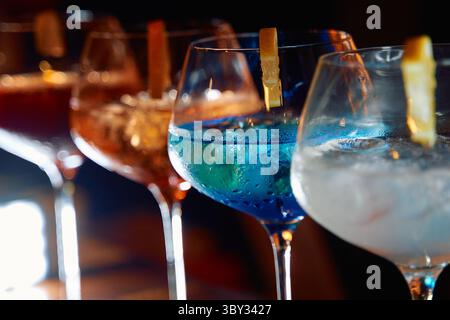 A colorful array of cocktails in elegant glasses featuring vibrant blue and orange hues, garnished with citrus peels, perfect for festive celebrations Stock Photo