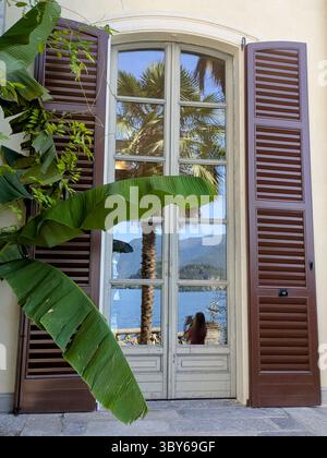 Window with shutters and banana leaf at villa monastero Stock Photo