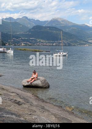 Woman sitting on a stone reading a book Stock Photo
