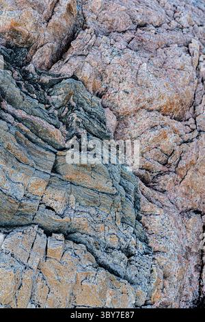 Close-up of colourful textured rock surface with natural striations and layered geological patterns. Stock Photo