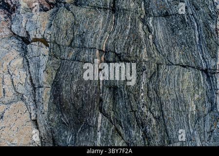 Close-up of colourful textured rock surface with natural striations and layered geological patterns. Stock Photo