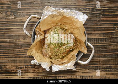A perfectly roasted turkey thigh, seasoned with herbs and spices, rests on a bed of parchment paper inside a roasting pan. The warm, golden skin glist Stock Photo