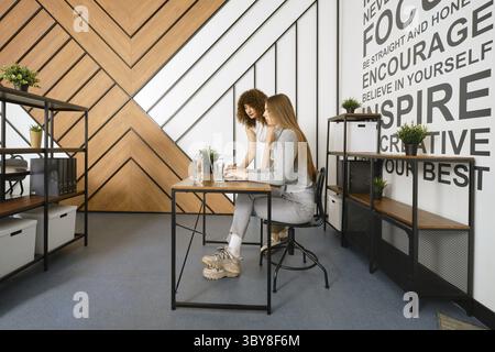 Two women are collaborating on a project in a stylish, modern office designed for a startup focused on women's health Stock Photo