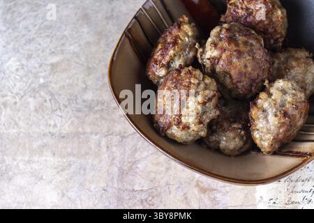Meatballs lie in a clay plate on a vintage beige background, space for text Stock Photo