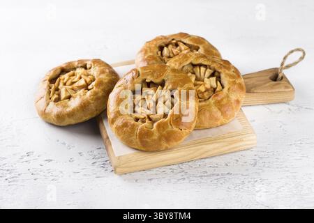 Food, Sweet mini pies with apples and cinnamon on a wooden board on a light gray background. Delicious homemade food Stock Photo