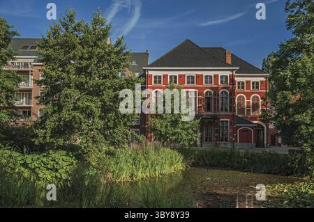 Evergreen garden and pond with mansions on sunset in Tielt. Charming and quiet village in the countryside, near Ghent and surrounded by agricultural f Stock Photo