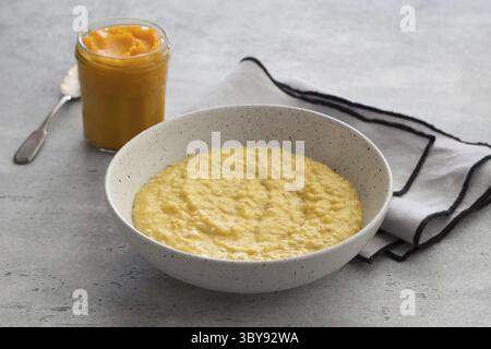 Food, Bowl of oatmeal with pumpkin on a gray textured background. Delicious healthy homemade breakfast Stock Photo