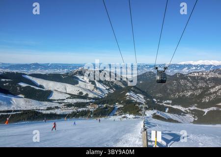 Low Tatras. Slovak ski resort Jasna in sunny weather. Ski slope and lift cabin. Blue sky over the mountain peaks Stock Photo