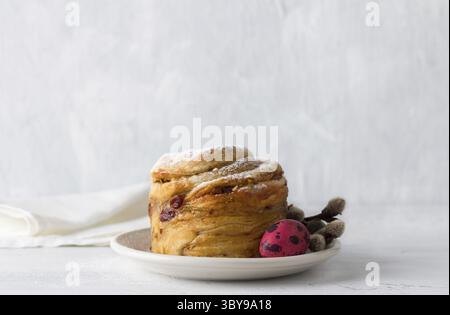 Food, Easter cake Kraffin with nuts and dried fruits, sprinkled with powdered sugar, decorated with a painted egg and willow branches on a light blue Stock Photo