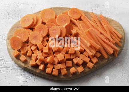 Food, Cubes, bars, slices of fresh ripe carrots on a wooden board, three types of cutting vegetables. Healthy diet food Stock Photo