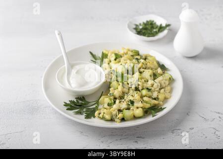 Food, Turkish scrambled eggs with zucchini served with yogurt on a light blue background. Delicious homemade vegetarian food Stock Photo