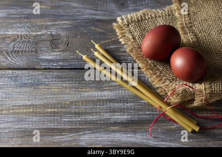 Food, Red easter eggs and beeswax candles on burlap over rustic wooden table for holiday tradition.photo Stock Photo