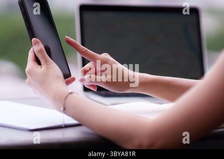 Close up adult hands navigating mobile device. Documents near laptop in dynamic workspace. Illustrates contemporary professionalism, connected workflo Stock Photo