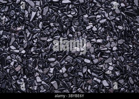 Top view of a stacks of polished natural Obsidian gravel chips on black background Stock Photo