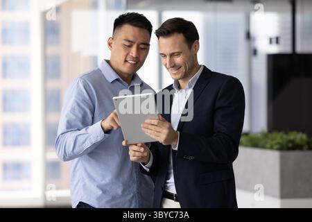 Men teammates reviewing documents or reports using tablet Stock Photo
