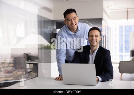Two projects managers posing in modern workplace with laptop Stock Photo