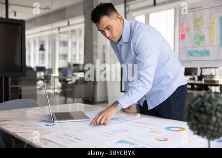 Serious Chinese businessman, financial analyst or auditor reviewing infographic data Stock Photo