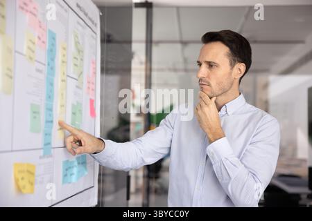 Man reviewing corporate goals written on attached sticky-notes Stock Photo