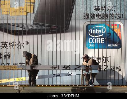 December 18, 2009, BEIJING, CHINA: Two Chinese workers install a massive computer billboard, featuring IBM laptops bundled with Microsoft software, at a electronics store in Beijing on December 18, 2009.  China will become Microsoft's biggest market within the next seven years, according to Bill Gates. (Credit Image: © Stephen Shaver/ZUMA Press Wire) Stock Photo