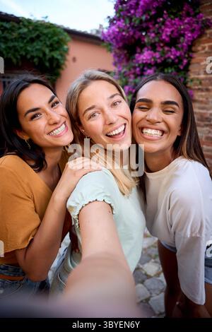 Three happy multi-ethnic friends taking a selfie on vacation in italy Stock Photo
