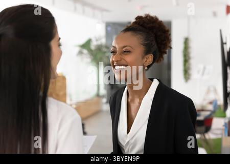 Happy woman enjoying friendly conversation during break in coworking space Stock Photo